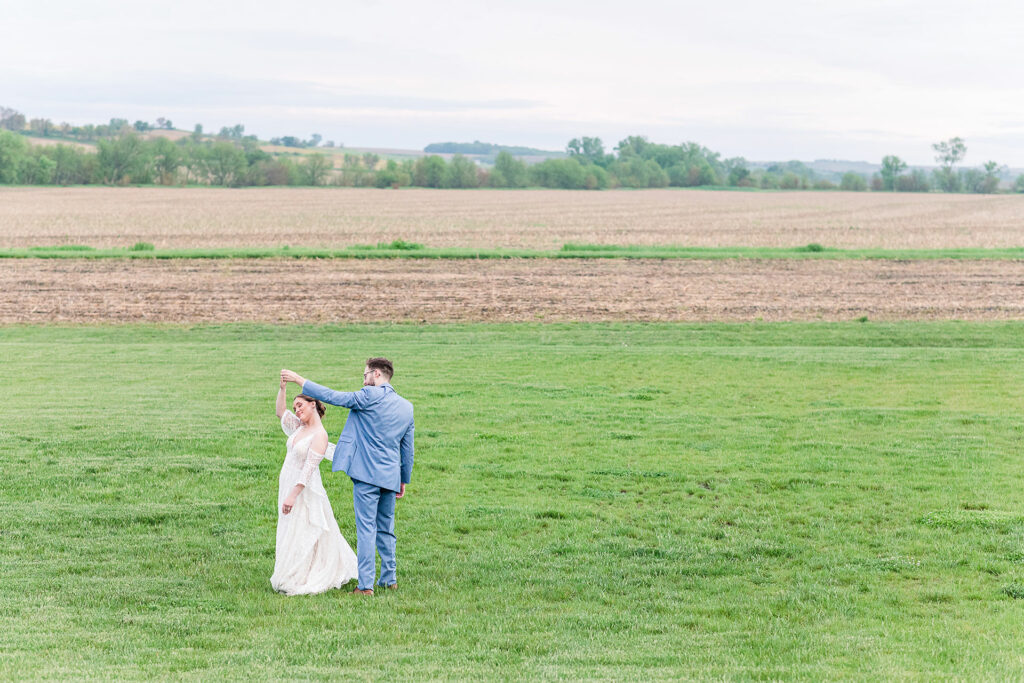 Bride and groom twirl in field | Emma Christine Creative