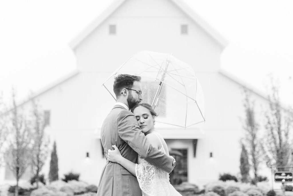 Bride and groom embrace under umbrella | Emma Christine Creative